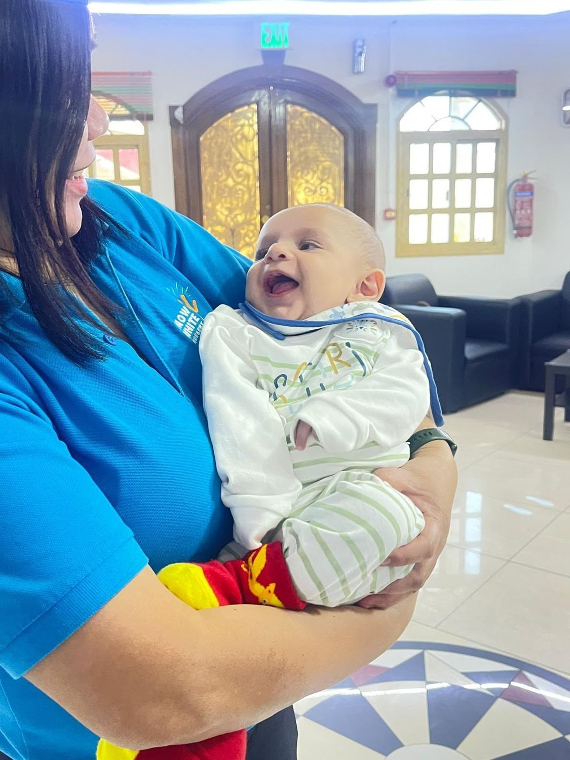 A teacher gently cradling a baby in the baby room